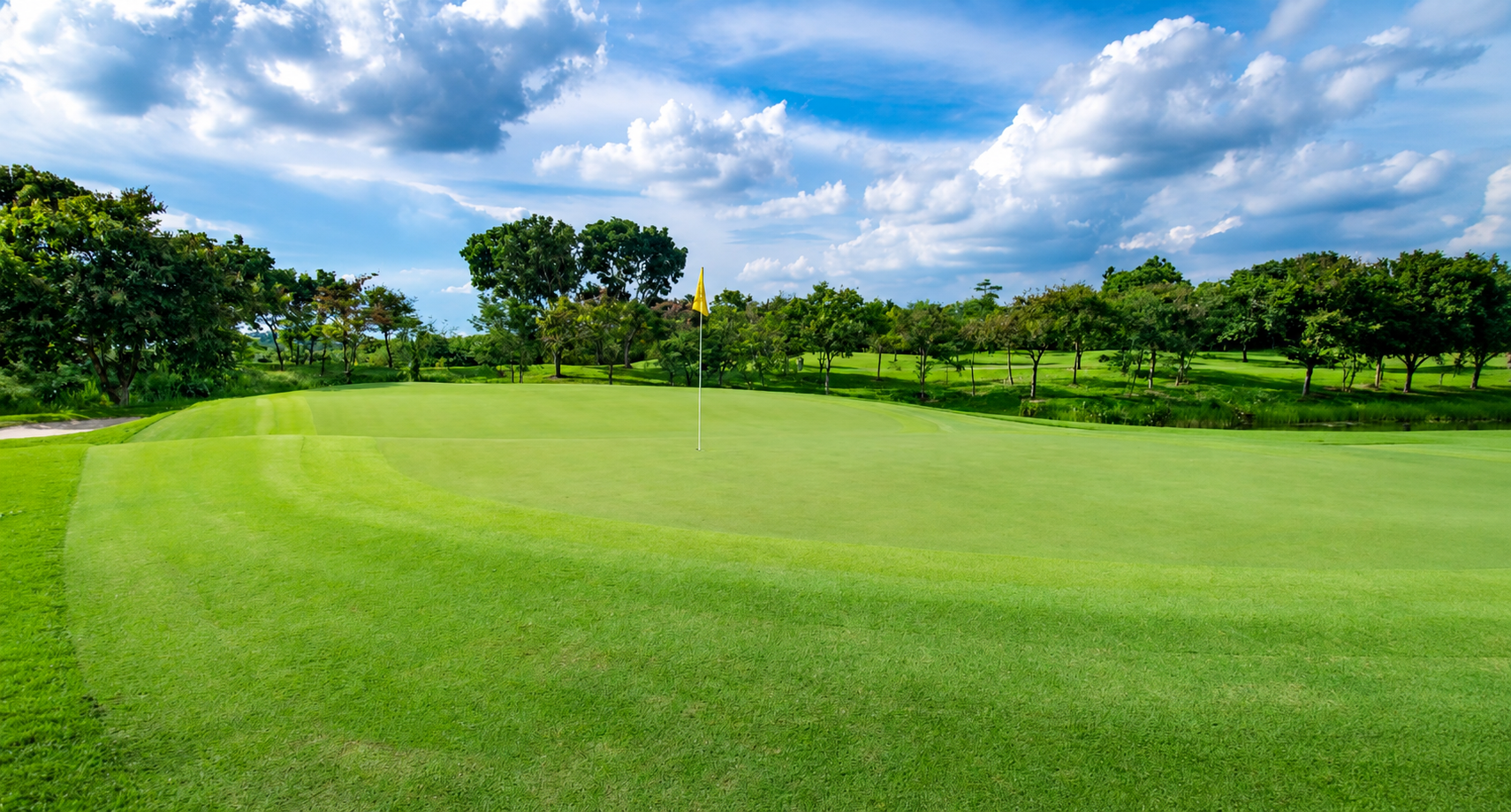 Groene golfbaan met vlag onder een blauwe lucht